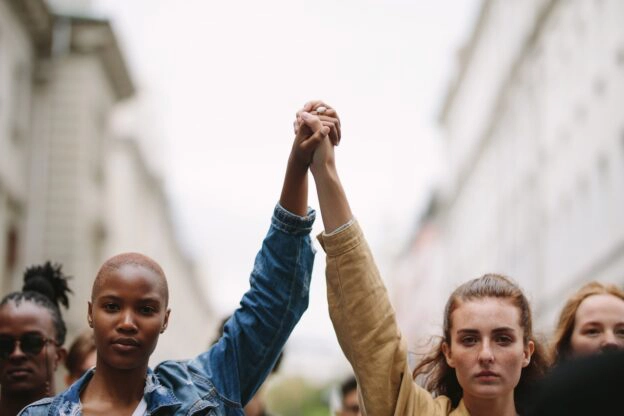 Two women holding hands up in protest