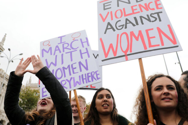 Young women with placards march at a rally to end violence against women